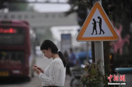 资料图：重庆一红绿灯处摆放“不做低头族、关注红绿灯”警示牌，提醒市民在过斑马线的时候不能玩手机。 陈超 摄
