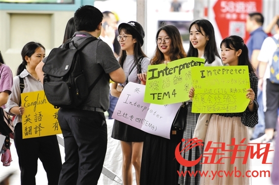4月13日，大学生们举着手中的彩色牌子在广交会展馆门前应聘翻译
