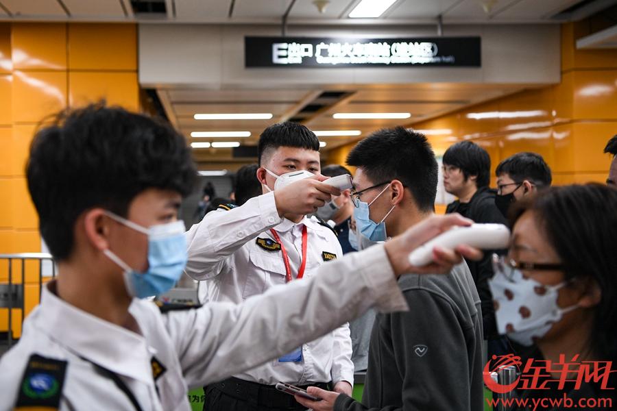 1月22日,广州南站地铁站的工作人员正在为进站旅客测量体温.